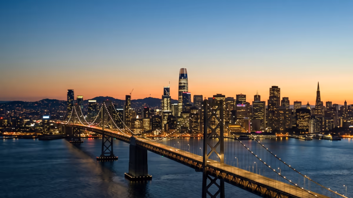 California LLC franchise tax voucher and Statement of Information form on a desk with a San Francisco skyline