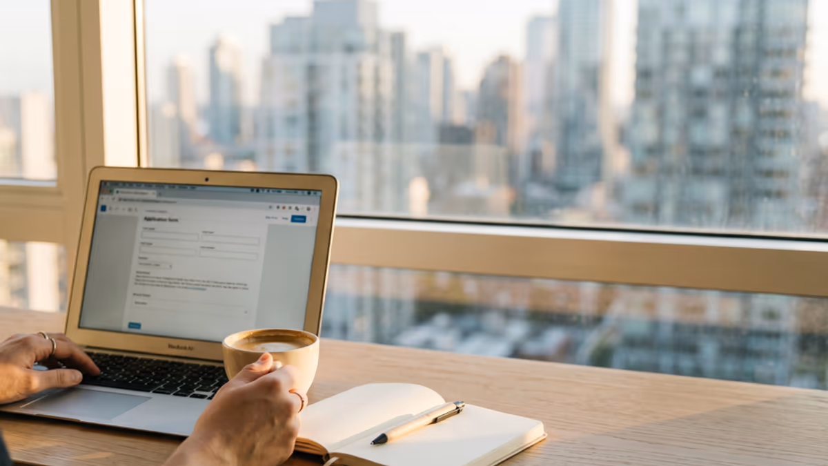 Empty modern coworking desk with laptop, plant, and coffee cup being cleared during a workspace transition