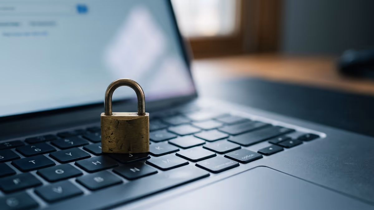 A small brass padlock resting on a laptop keyboard with a softly glowing screen behind it, representing privacy for a domain registration