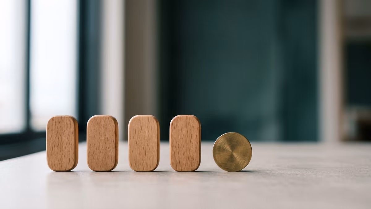 Four small wooden markers arranged in an even sequence beside a single brass coin, symbolizing quarterly payroll tax filing