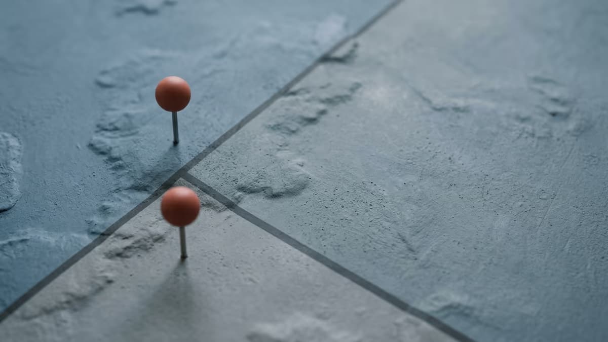 Two identical map pins standing on opposite sides of a state boundary line on a minimalist unlabeled map
