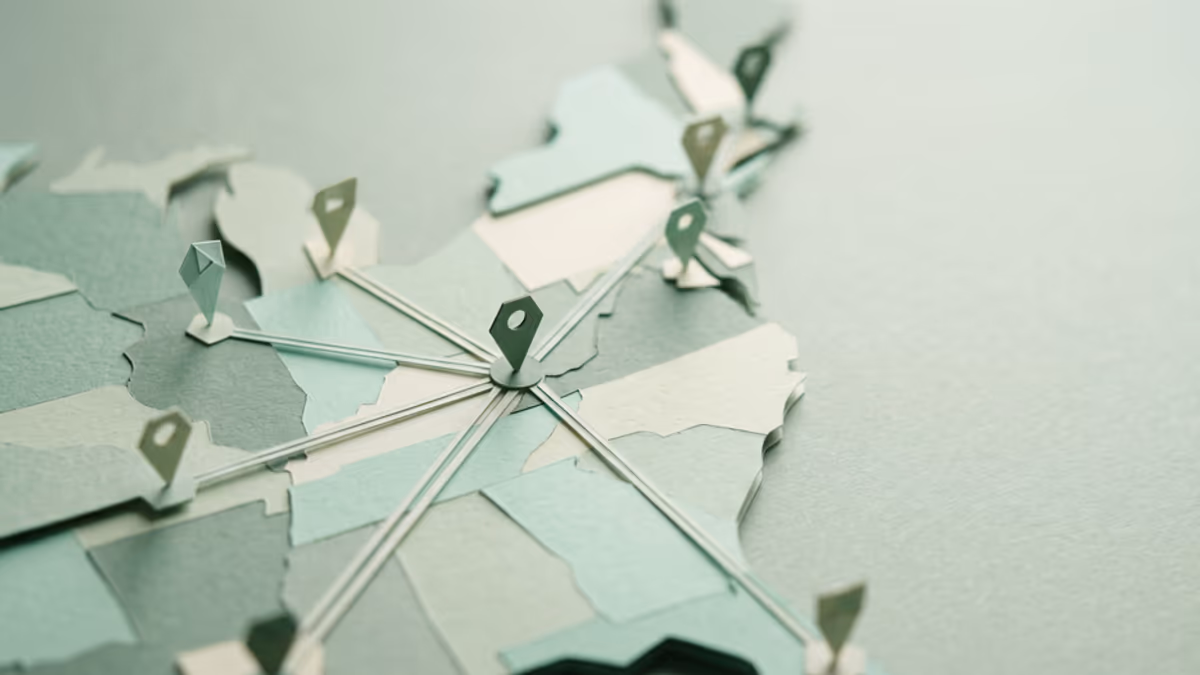 A wide, low-angle macro of a geometric paper map abstraction with route lines connecting several points across a muted green surface, soft directional light, editorial composition with negative space on the right