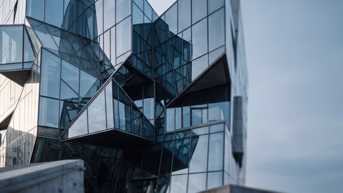 Abstract modern architectural facade with stacked glass boxes and geometric intersecting planes in a cool blue and steel gray palette, soft natural light, editorial blog hero composition