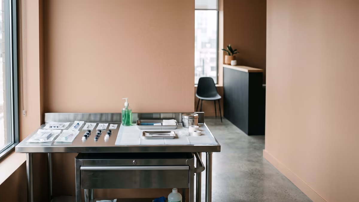 A clean, modern tattoo studio interior with a tidy stainless prep station and a minimal reception corner, representing a licensed body-art business with a physical location