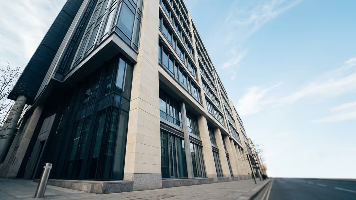 Looking up at the facade of a modern commercial office building against a bright sky, representing a real business street address