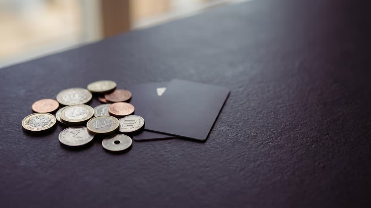 Assorted international coins arranged beside two plain payment cards, representing a multi-currency business account