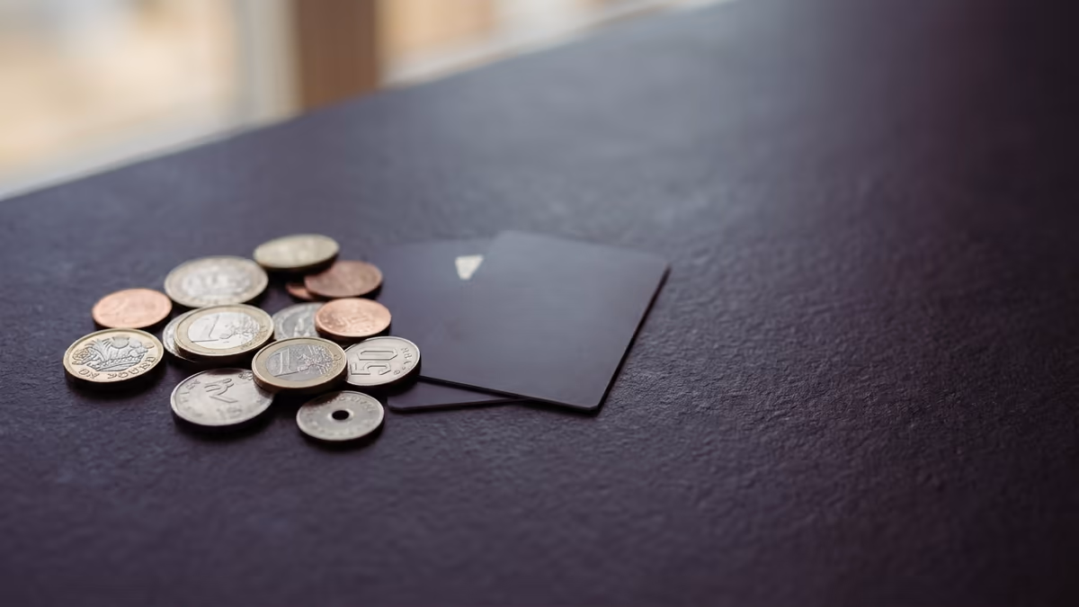 Assorted international coins arranged beside two plain payment cards, representing a multi-currency business account